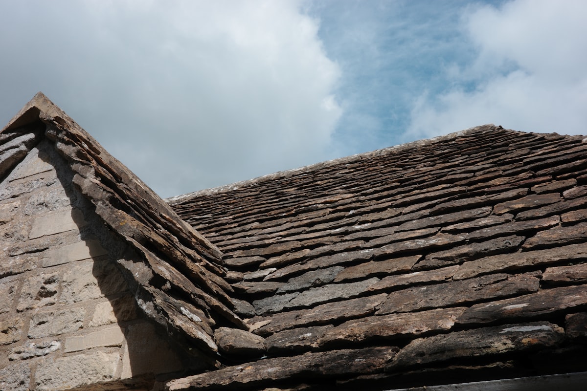 Weathered Vermont slate roof tiles against a cloudy sky